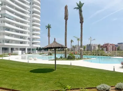 a resort with a swimming pool and palm trees at Gran Canet Salva, moderno apartamento con terraza y vistas al mar in Canet de Berenguer