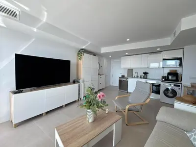 a living room with a flat screen tv and a kitchen at Gran Canet Salva, moderno apartamento con terraza y vistas al mar in Canet de Berenguer