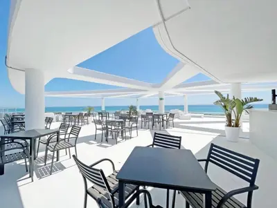 an outdoor patio with tables and chairs and the ocean at Gran Canet Salva, moderno apartamento con terraza y vistas al mar in Canet de Berenguer