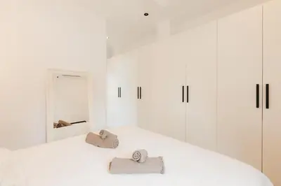 a white bedroom with white cabinets and towels on a bed at Spacious villa with private pool & garden for 4 in Partida de La Cañada