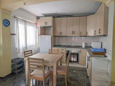 a kitchen with a table and chairs and a refrigerator at Brisa del Puerto in Puerto de Sagunto