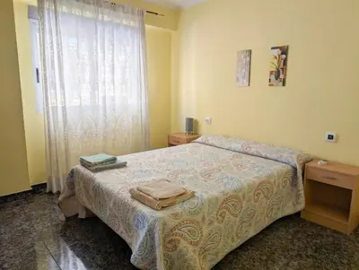 a bedroom with a bed and two night stands and a window at Brisa del Puerto in Puerto de Sagunto