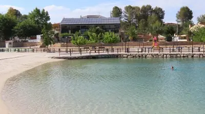 a pool of water next to a beach with a building at Casa EL CRUCE Navarrés in Navarrés