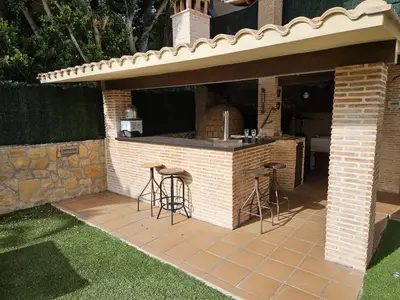 an outdoor kitchen with stools in a brick building at Amazing Villa with swimming pool in El Vedat de Torrente in Torrent