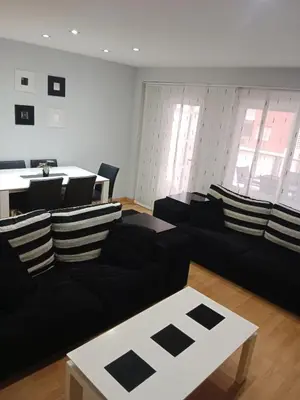 a living room with a black couch and a table at Nules Beach Apartment in Moncófar