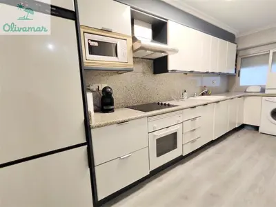 a kitchen with white cabinets and a refrigerator at Apartamento céntrico y cerca del mar en Tavernes in Tavernes de Valldigna