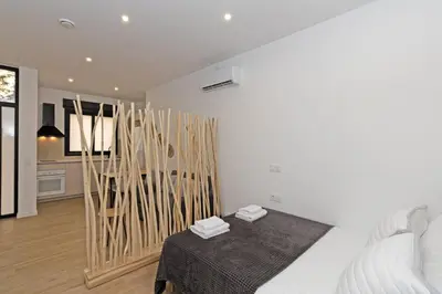 a white bedroom with a bed and wooden sticks at GuestReady - Lovely stay in the Algirós area in Valencia