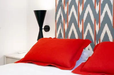 a bed with two red pillows and a lamp at La Casa del Mar-Cabañal 3BR Suites in Valencia