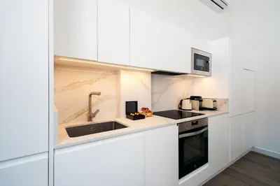 a kitchen with white cabinets and a sink at La Casa del Mar-Cabañal 3BR Suites in Valencia