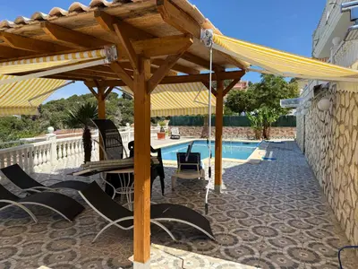 a wooden pergola next to a swimming pool at Villa avec superbe vue in Cullera