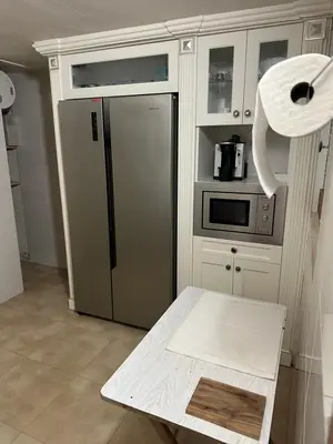 a kitchen with a stainless steel refrigerator and a table at Habitaciones Espacio in Corbera de Alcira
