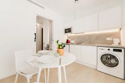 a white kitchen with a table and a washing machine at Fantástico loft en Valencia in Valencia