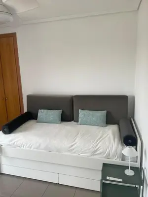 a white bed with two blue pillows on it at Patacona beach apartment in Valencia