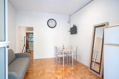 a living room with a table and a clock on the wall at Loft Economico Cerca del Centro 1 Domitorio y Sofa cama 4pax AC in Valencia