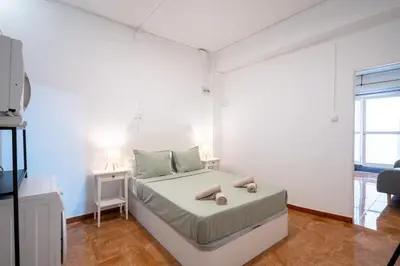 a white bedroom with a bed and a tv at Loft Economico Cerca del Centro 1 Domitorio y Sofa cama 4pax AC in Valencia