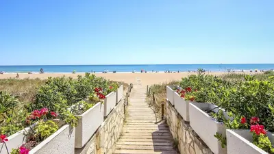 a staircase leading to the beach with flowers at Cozy Beachside Apartment in Tavernes de Valldigna