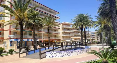a building with palm trees in front of it at Cozy Beachside Apartment in Tavernes de Valldigna