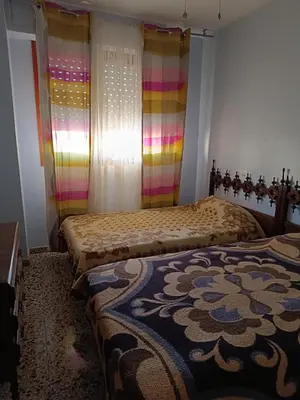 two beds in a bedroom with rainbow curtains at Cozy Beachside Apartment in Tavernes de Valldigna