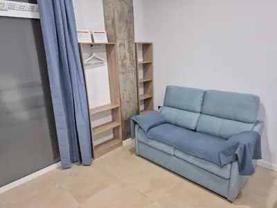 a blue couch in a room with a shelf at Beach and City Valencia in Valencia