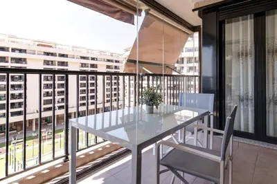a table and chairs on a balcony with a view of a city at Beach apartment in Valencia