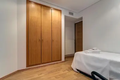 a bedroom with a bed and a wooden cabinet at Beach apartment in Valencia