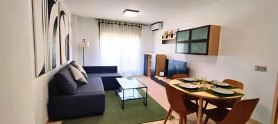a living room with a blue couch and a table at Apartamento cerca Playa in Puerto de Sagunto