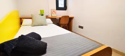 a small room with a bed with a yellow and white at Apartamento cerca Playa in Puerto de Sagunto