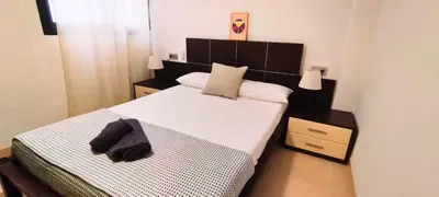 a small bedroom with a large bed with white sheets at Apartamento cerca Playa in Puerto de Sagunto