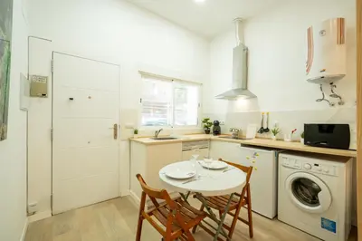 a kitchen with a table and two chairs and a washing machine at Loft Centrico 2 pax Poyector TV in Valencia