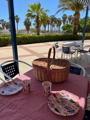 a picnic table with a basket and plates on it at Beachfront Family Appartment with Pool in Valencia