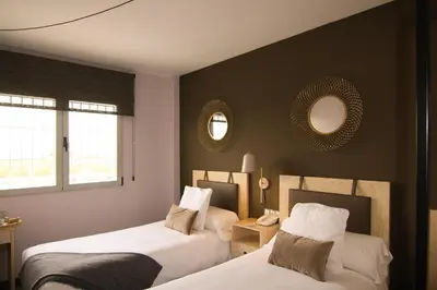 two beds in a room with two mirrors on the wall at El Puig in El Puig