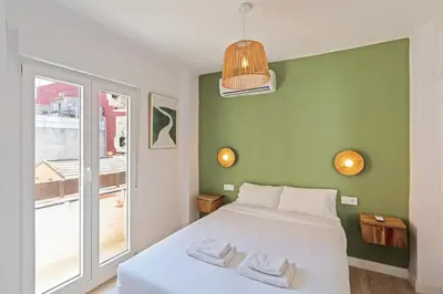 a bedroom with a white bed and a green wall at GuestReady - Lovely family home in El Cabanyal in Valencia