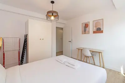 a white bedroom with a bed and a table at GuestReady - Lovely family home in El Cabanyal in Valencia