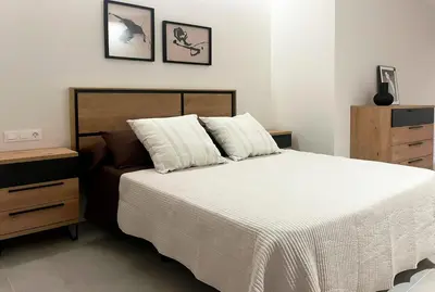 a bedroom with a bed with white sheets and a dresser at Apartamento Estilo in Valencia