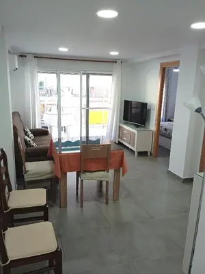 a living room with a table and chairs and a tv at Nautic, 4-I in Cullera