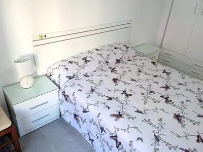 a small bedroom with a bed with a floral bedspread at Nautic, 4-I in Cullera