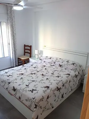 a bedroom with a bed with a floral bedspread at Nautic, 4-I in Cullera