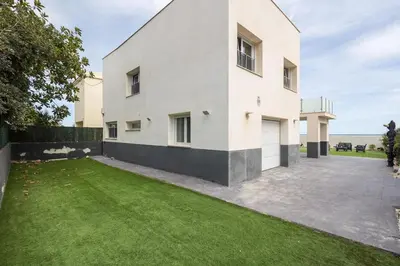 a white house with a green lawn in front of it at Villa Prestige Beach in Mareny Barraquetas
