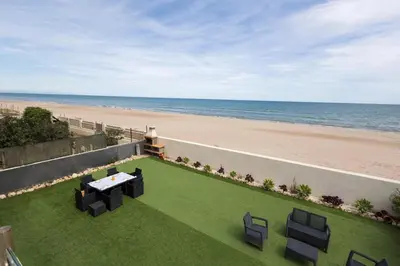 a patio with a table and chairs and the beach at Villa Prestige Beach in Mareny Barraquetas
