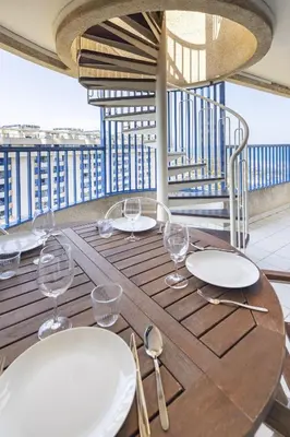a wooden table with plates and glasses on a balcony at ApartUP Patacona Splendor in Valencia
