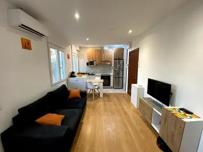 a living room with a black couch and a kitchen at Bright & Quiet Apartment Close to Central Valencia in Valencia