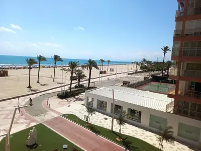 a building next to a beach with palm trees and the ocean at Sol, 3-20 in Cullera