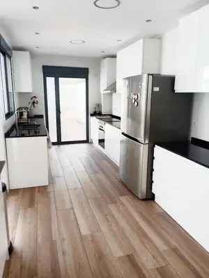 a kitchen with white cabinets and a wooden floor at Casa con PISCINA y CINE in Paterna