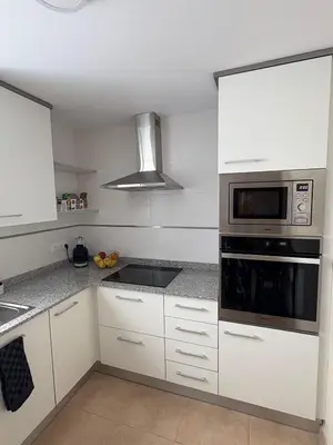 a kitchen with white cabinets and a microwave at Seira Apartment in Burriana