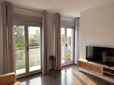 a living room with a flat screen tv and large windows at Apartamento turístico Playa Valencia in Valencia