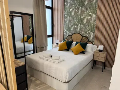 a bedroom with a bed with yellow pillows and a mirror at Apartamento El Rincón de Darío in Valencia