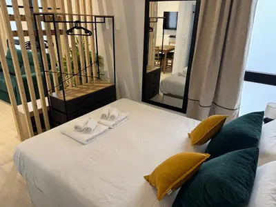 a bedroom with a white bed with yellow pillows and a mirror at Apartamento El Rincón de Darío in Valencia