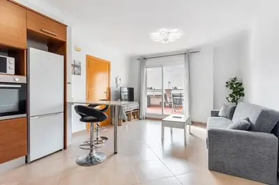 a living room with a couch and a table and a kitchen at Acogedor y excelente ubicación in Puerto de Sagunto
