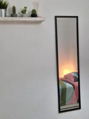 a mirror hanging on a wall next to a bed at All you need in Valencia