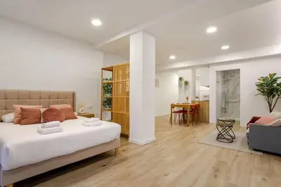 a bedroom with a large bed and a living room at Bright & Modern Apartment - Rose y Maya in Valencia